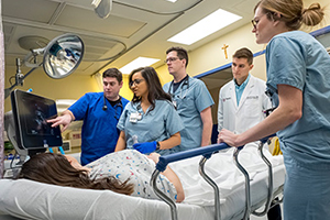 Several nursing and medical students examine a simulated patient's results.