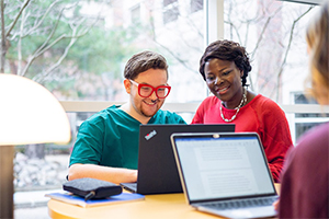 A nursing student works on a laptop with health professions faculty.