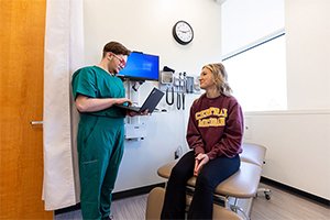 A nursing student holds a laptop to record patient information in a simulation.