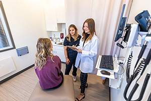 A nursing student and a faculty member talk with a standardized patient