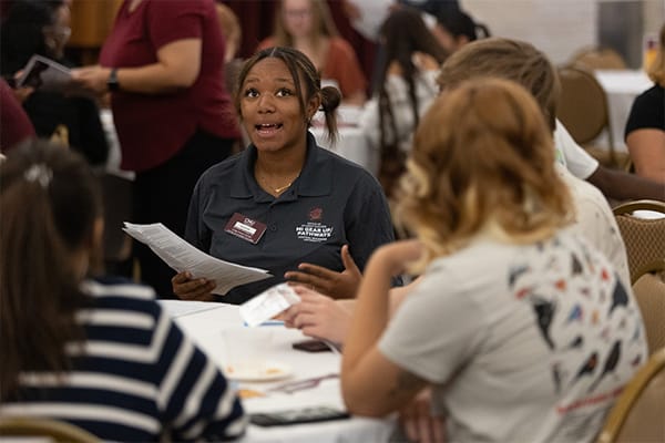 A mentor talks with students at an event in the UC Rotunda.