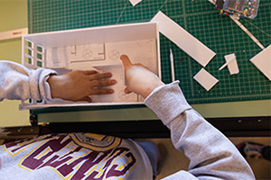 An interior design student lays out rooms in a scale model house.