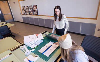 Two interior design students work on a scale model project.