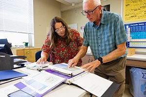 a man and woman looking at a folder together