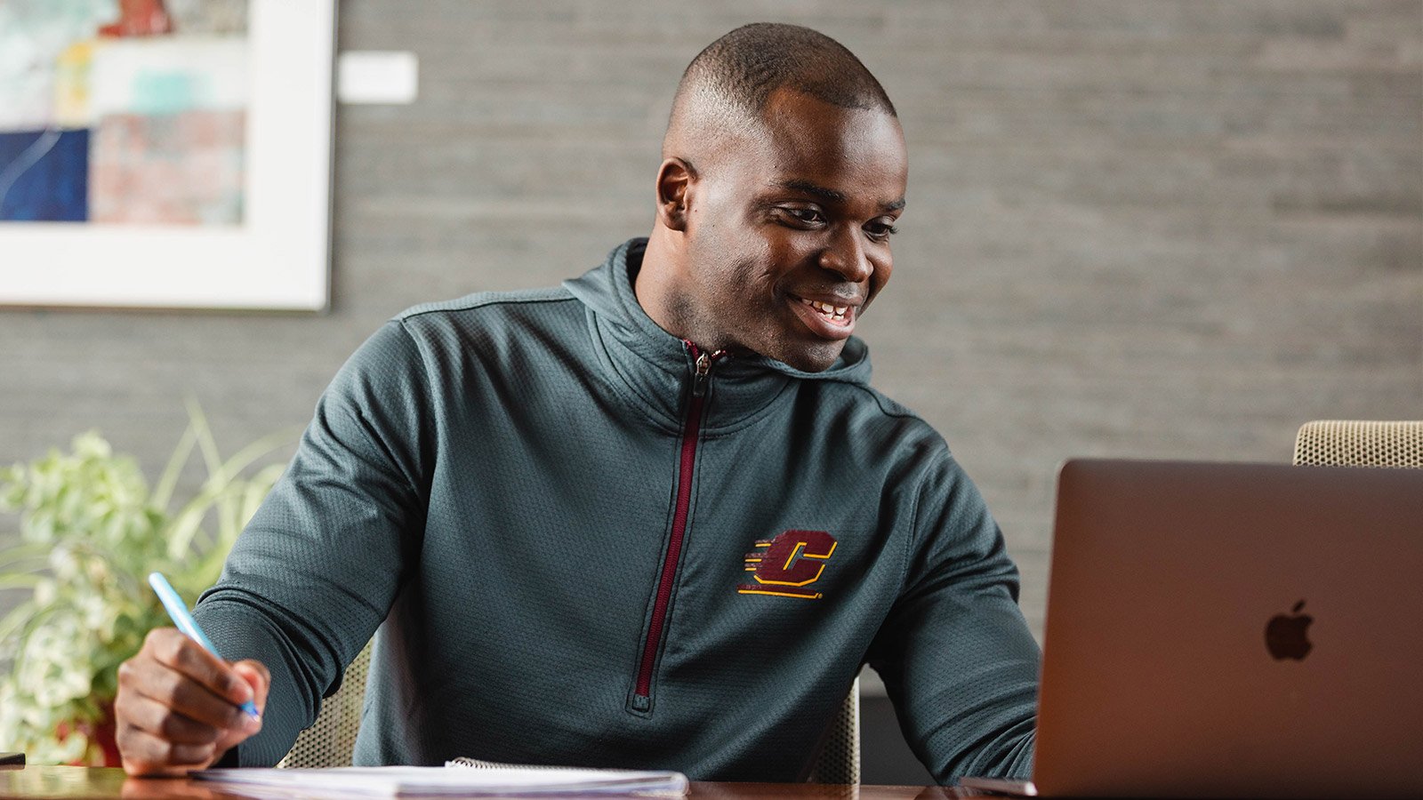 A male military student works on his computer completing an assignment from his online class instructor.