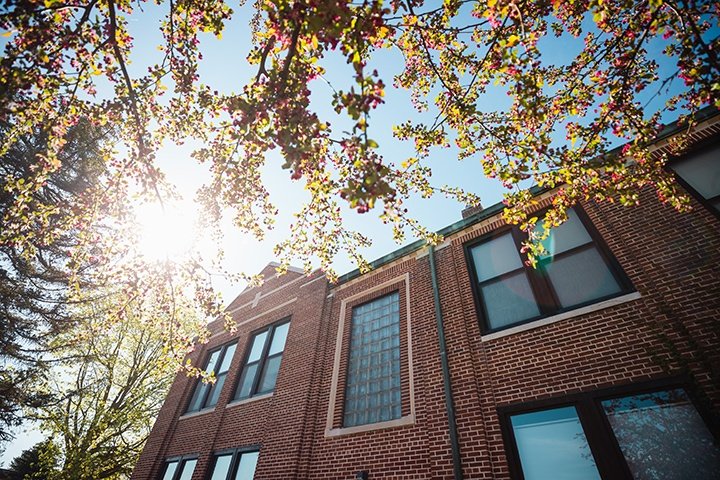 The sun peeks through over Warriner Hall.