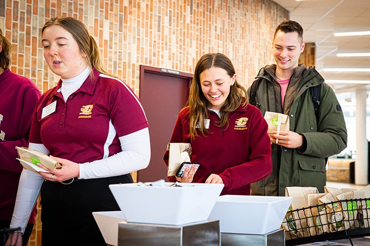 Students walk take various snacks from a table set up in a hallway inside the University Center.