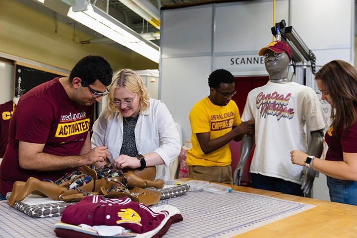 Four college students work on clothing and with a mannequin in a fashion lab.