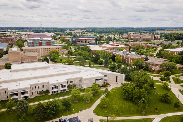 An aerial view of Central Michigan University's campus shows freshly mowed gras, a large green tree and many buildings.
