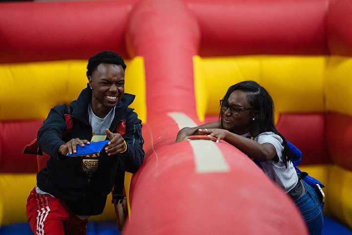 Two students smile while standing in an inflatable bounce house.