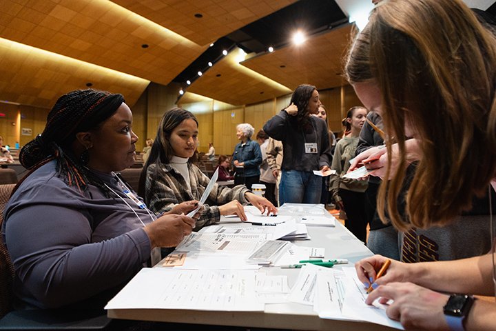 Students sit at a table taking part in the 2023 Poverty Simulator.