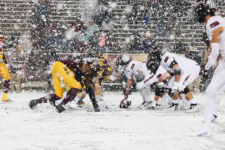 On an extremely snowy night, the CMU and Northern Illinois offensive and defensive lines prepare to run a play on the Kelly/Shorts turf.