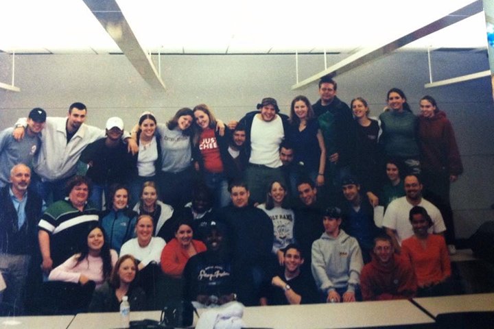A photo from 2002 shows a large group of students huddling together for a group photo.