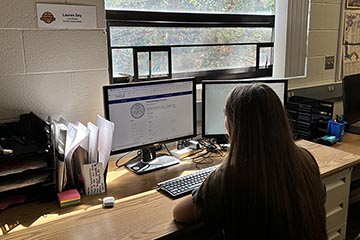 A young woman inputs data into a desktop computer in an office.