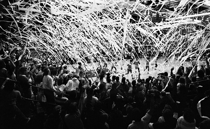 A black and white photo from 1987 shows rolls of toilet paper streaming down onto a basketball court.