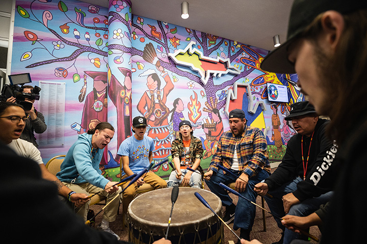 Members of the Saginaw Chippewa Indian Tribe pound a ceremonial drum, commemorating the unveiling of a mural honoring their history in the Bovee University Center.