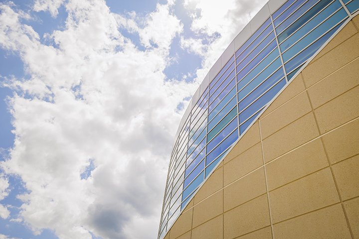 Blue skies and large, fluffy white clouds sit above the Charles V. Park Library.