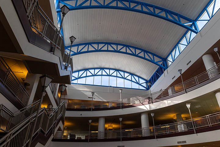 A view inside the Park Library looking up from the first floor towards the top. Stairways and railings along on the outer edges are lined with lamp posts.