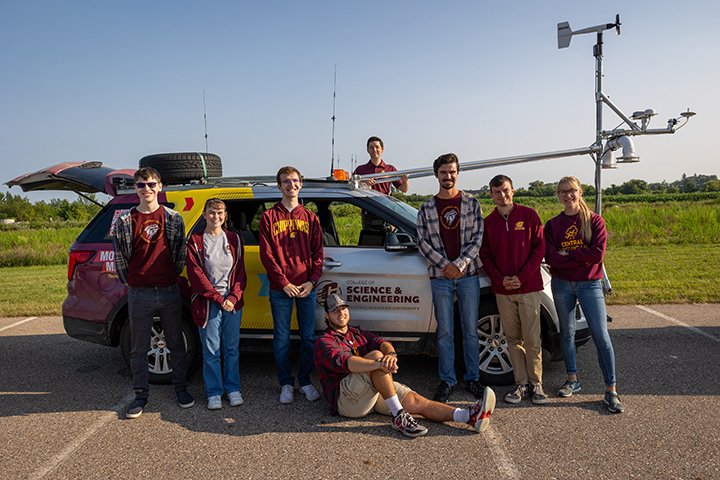 Jason Keeler and group of CMU students stand next to a mobile weather vehicle.