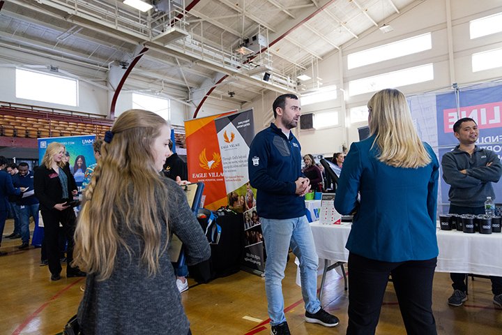 Inside Finch Fieldhouse, Students speak with an employer during a career fair.