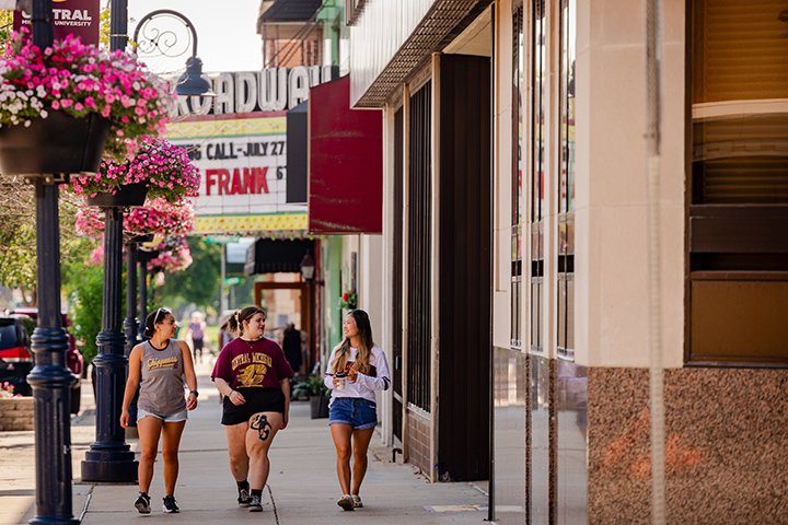 Three CMU students walk down the sidewalk past the Broadway Theatre in downtown Mt. Pleasant.