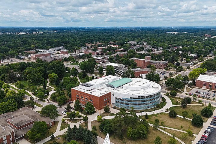 An aerial view of Central Michigan University’s campus with the Park Library at its center. The horizon stretches for miles with fluffy clouds against a light blue sky.