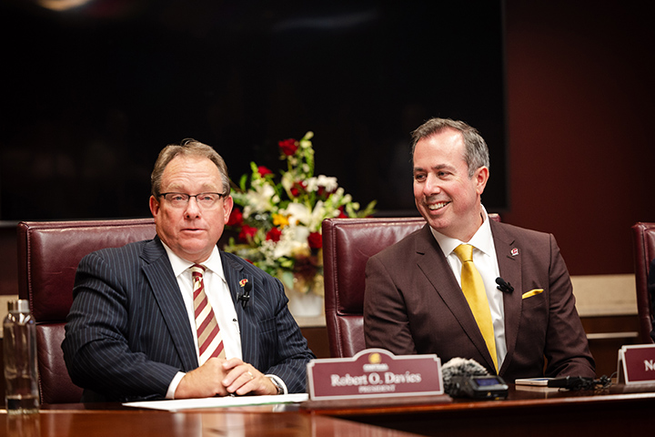 CMU President Bob Davies and President-Elect Neil MacKinnon sit next to each other at a large table.