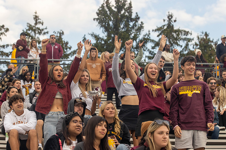 CMU students raise their arms and cheer from the stands inside Kelly/Shorts Stadium.