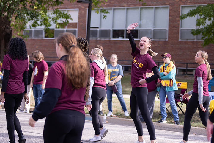 A Dance and Theatre student waves while walking in the homecoming parade.