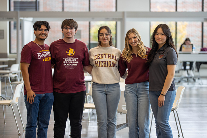 Five CMU students stand together for an indoor group photo.