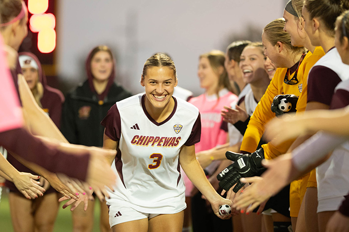 A CMU soccer player runs through a tunnel of people receiving high fives.