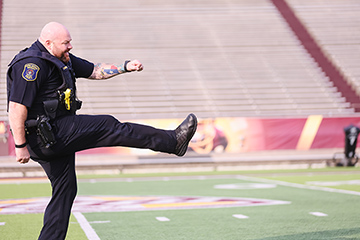 A member of the CMU Police Department punts a football inside Kelly/Shorts Stadium.