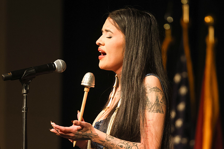 Tia Wood closes her eyes while singing and standing on stage.