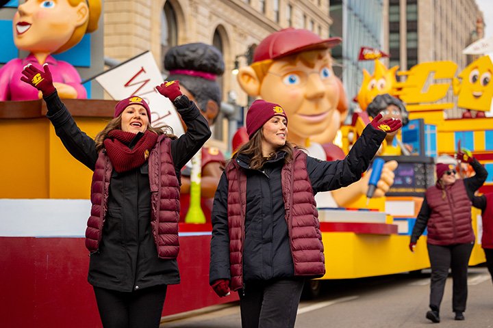 A closeup of two CMU parade volunteers waving at the crowd.