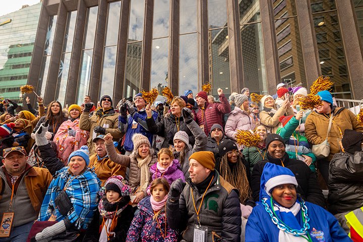 A crowd of people sit in the bleachers cheering and waving.