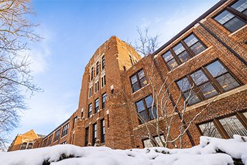 A tall brick building with snow on the ground.