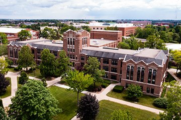 A large brick building with sidewalks, trees and grass.