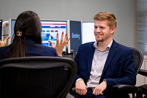 A man and woman sitting in chairs in a computer lab.