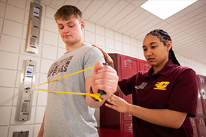 A physical therapy student using equipment to work with a patient.