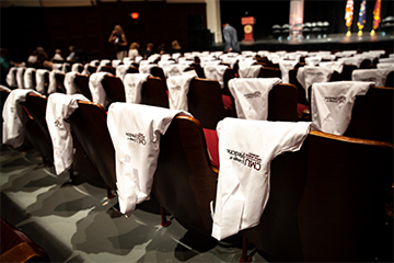 White medical doctors' coats draped over seats in an auditorium.