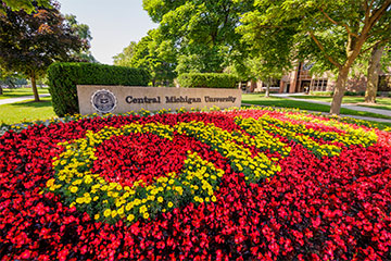 Red and yellow flowers spell out the word CMU near the Central Michigan University sign.