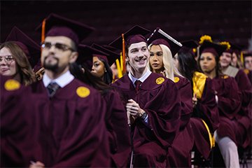 A group of people in maroon graduation gowns.