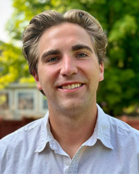 Close-up photo of a blond man in a blue button-down shirt