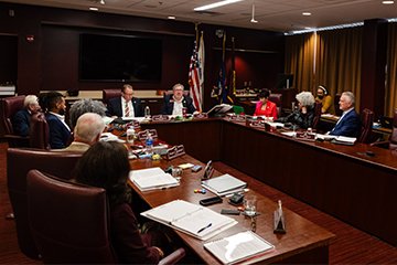 A group of people sitting at a table in a conference room.