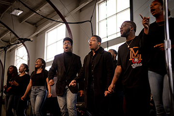 A choir sings on stage in Finch Fieldhouse.