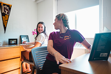 Two college students talking in a dorm room.