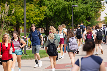 Dozens of college students walk down the path through the heart of CMU's campus.