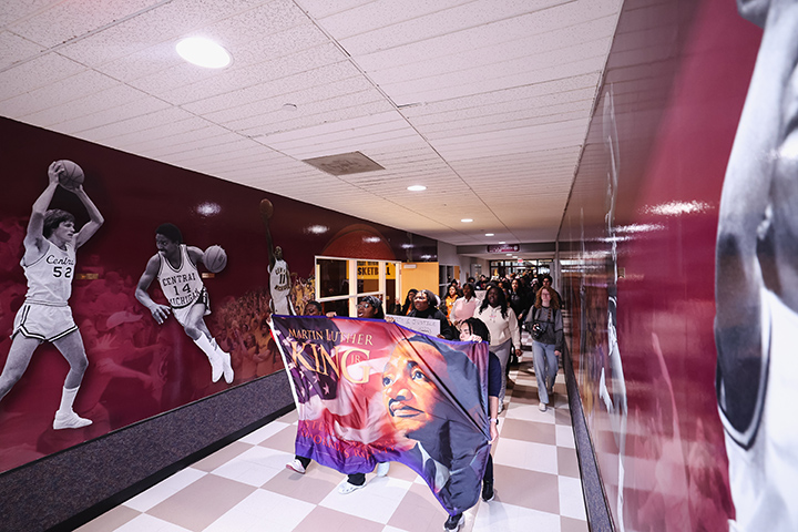 Students walk down a hallway holding an MLK banner.