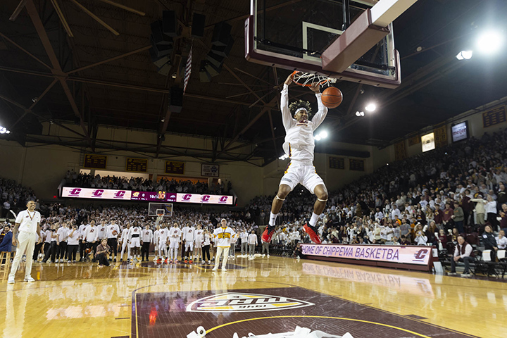 A CMU basketball player dunks a basketball in the hoop just prior to toilet paper rolls being tossed on the court.