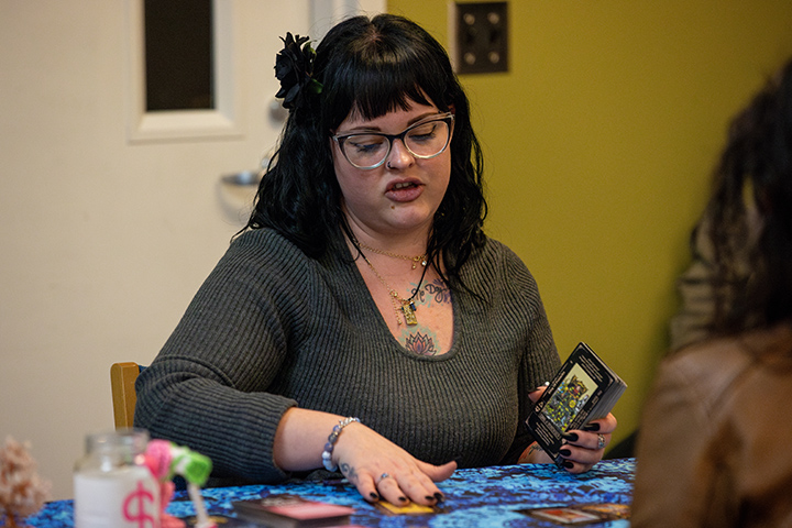 A tarot card reader sits at a table reading cards.